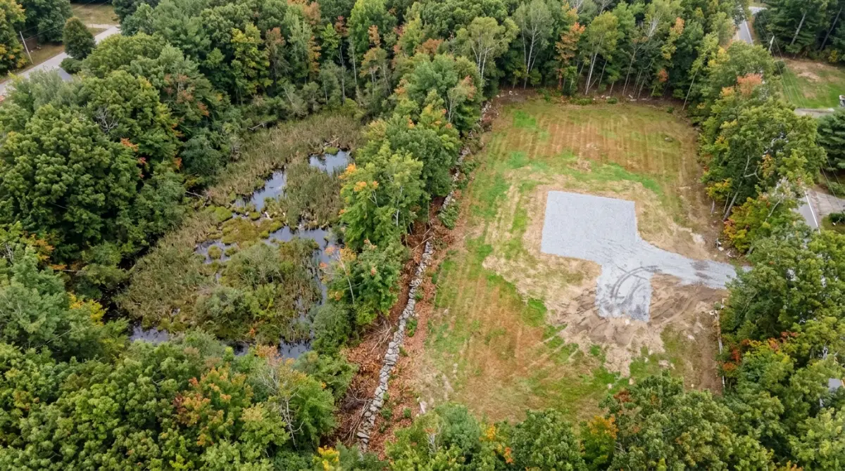 Aerial view of a Rhode Island building site beside a freshwater wetland and tree buffer